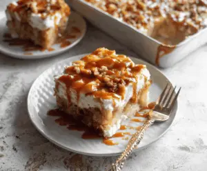 Delicious Caramel Apple Poke Cake topped with caramel drizzle and fresh apple slices, perfect for fall dessert