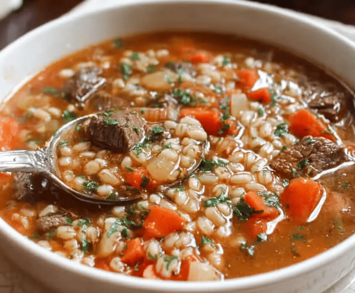 Hearty beef and barley soup in a bowl with fresh herbs and vegetables, perfect for a comforting meal