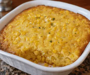 Delicious golden Corn Casserole topped with melted cheese and fresh herbs, served in a baking dish