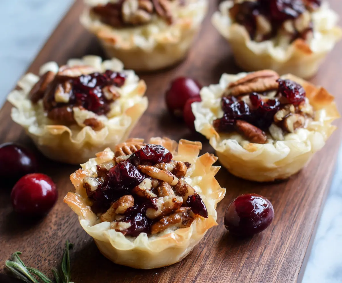 Cranberry Pecan Baked Brie Cups appetizer with creamy cheese, fresh cranberries, and pecans in flaky pastry cups.