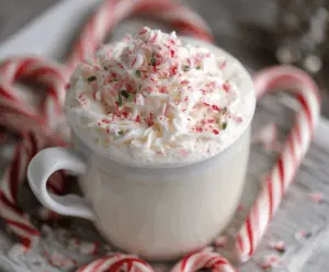 A warm cup of peppermint white hot chocolate topped with whipped cream and crushed peppermint candies.