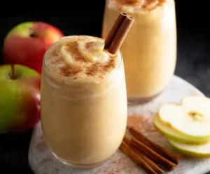 Creamy apple pie smoothie with cinnamon and whipped cream in a glass