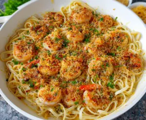 Delicious Cheesecake Factory Shrimp Scampi Linguine served on a white plate, garnished with parsley and lemon wedges.