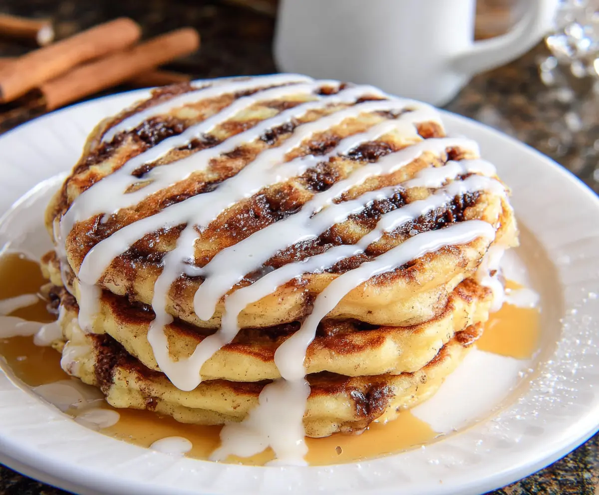Delicious cinnamon roll pancakes topped with icing and cinnamon sugar, perfect for breakfast or brunch.