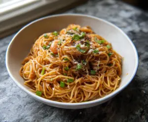 Delicious Asian garlic noodles garnished with chopped green onions and sesame seeds.