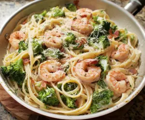Creamy broccoli and shrimp Alfredo served over pasta with fresh ingredients.