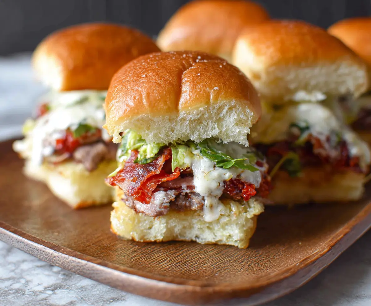 Delicious Italian Grinder Sliders with melted cheese, savory meats, and fresh toppings on soft rolls.