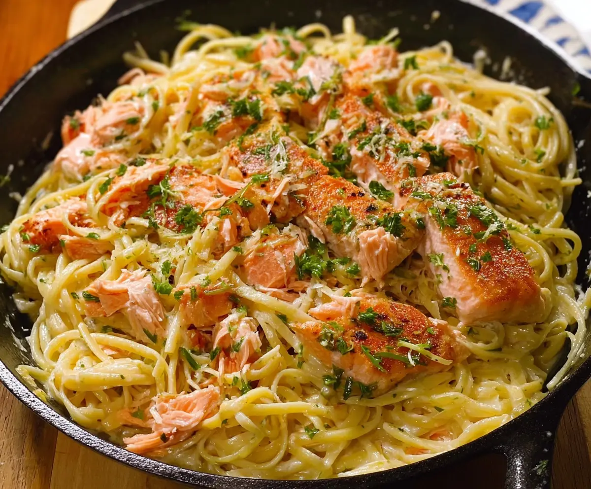 Creamy lemon butter salmon pasta served with fresh herbs on a white plate.