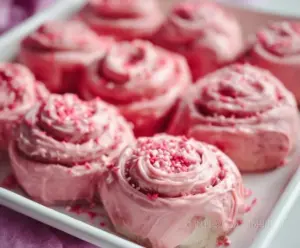 Delicious pink velvet cinnamon rolls topped with cream cheese frosting, perfect for breakfast or dessert.