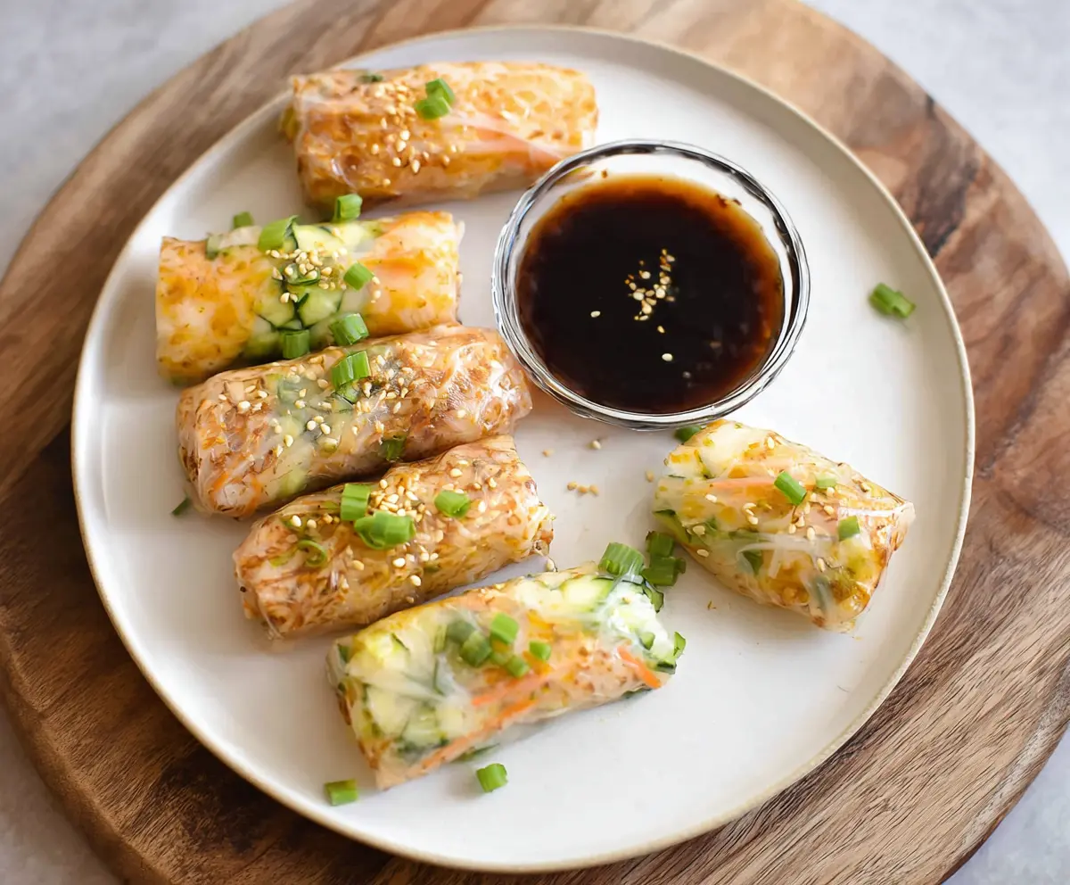 Crispy air fryer rice paper rolls filled with colorful vegetables and herbs on a white plate.