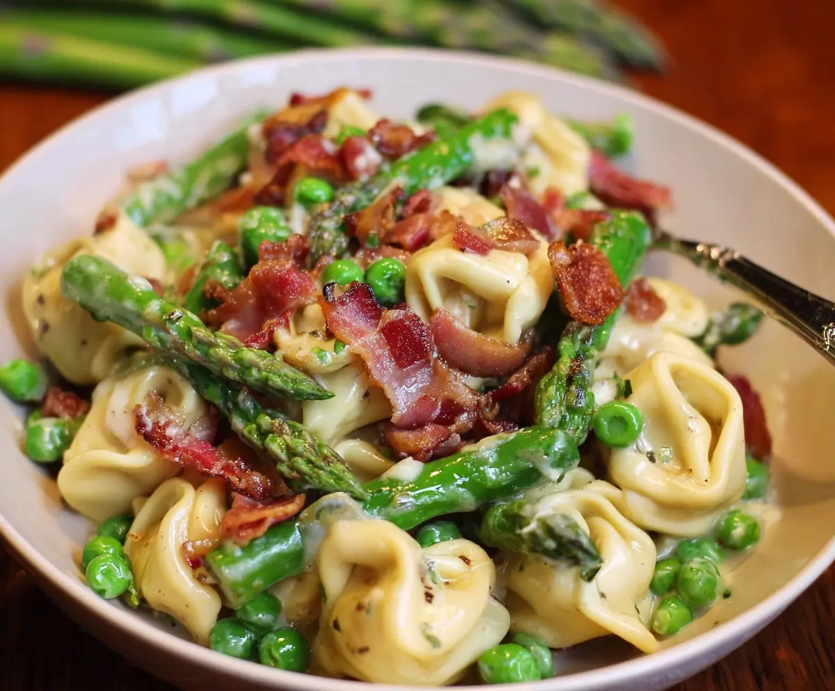 Delicious tortellini pasta with peas, asparagus, and crispy bacon on a plate, perfect for a flavorful meal.