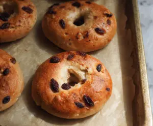 Fresh cinnamon raisin yogurt bagels on a plate, showcasing their golden-brown crust and appetizing texture.