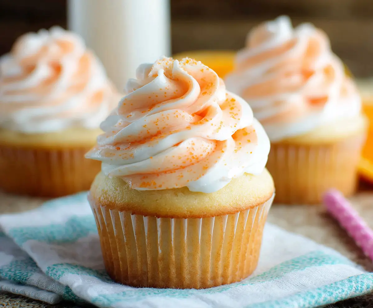 Delicious Orange Creamsicle Cupcakes topped with orange zest and creamy frosting.
